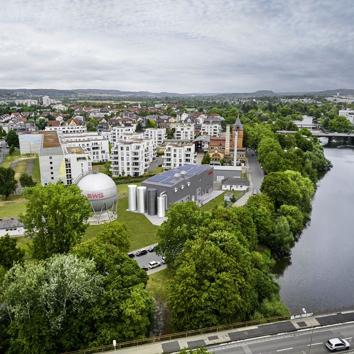 Aerial montage of the planned PowerLahn facility on the bank of the River Lahn, surrounded by trees and urban development in Gießen.